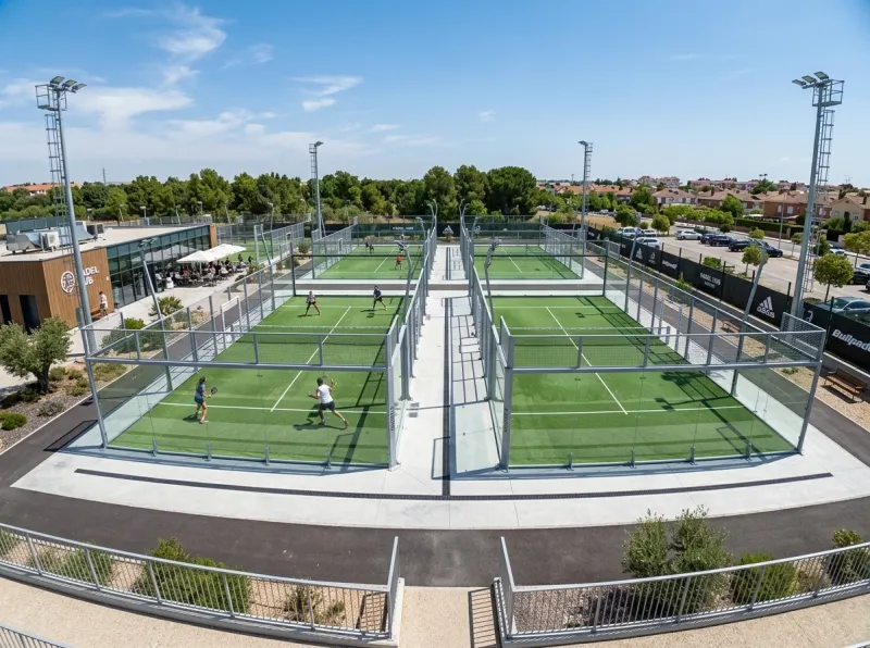 Vue aérienne d'un terrain de padel aux dimensions officielles 10x20 mètres avec parois vitrées, surface en gazon synthétique et éclairage LED réglementaire à 6 mètres de hauteur
